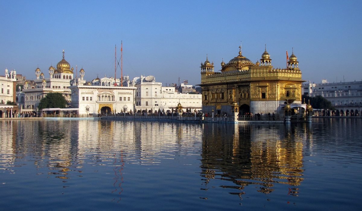 The Akal Takht and the golden Harmandir Sahib lit up at night across the sarovar in Amritsar