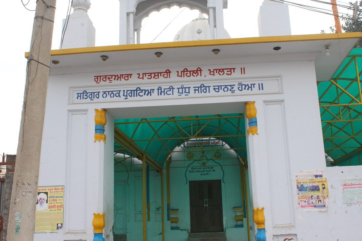 A white gurdwara building with a Nishan Sahib in the village of Khalra, Punjab