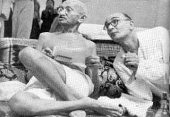 Gandhi seated beside his secretary Mahadev Desai at a meeting, both in white khadi