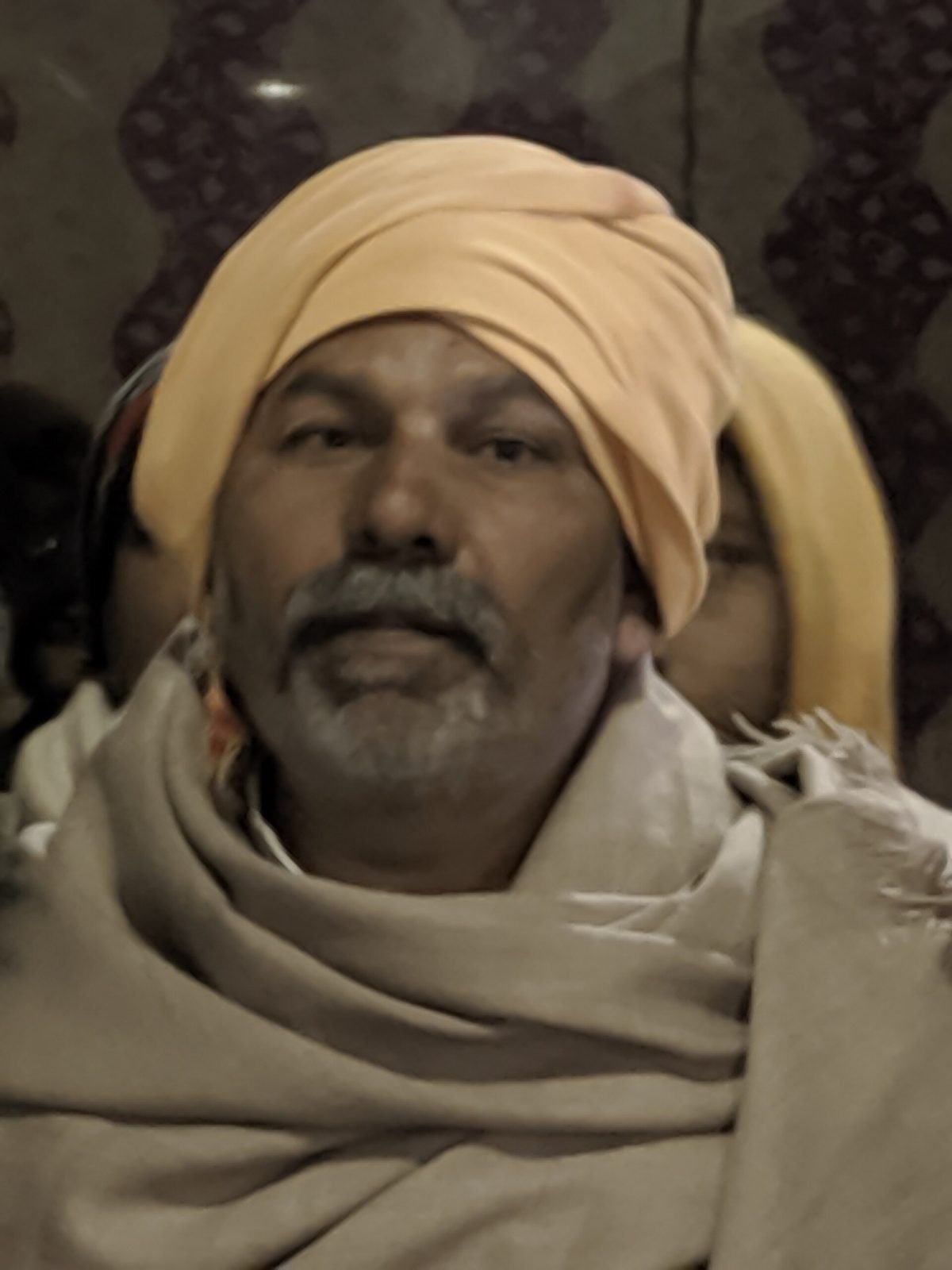 Farm leader Rakesh Tikait in a yellow turban and a grey shawl at night