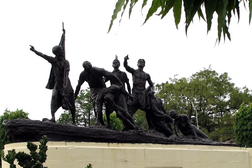 Bronze statue of seven young men carrying a flag, in front of a building in Patna