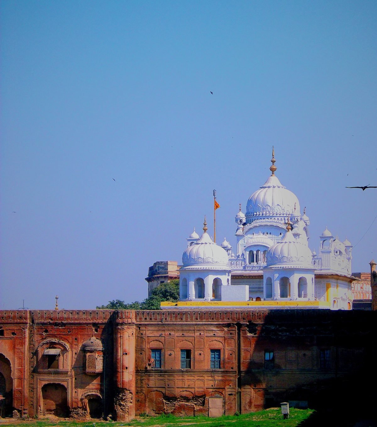 A white and cream building with a fluted gilded dome and small domed pavilions, against a blue sky