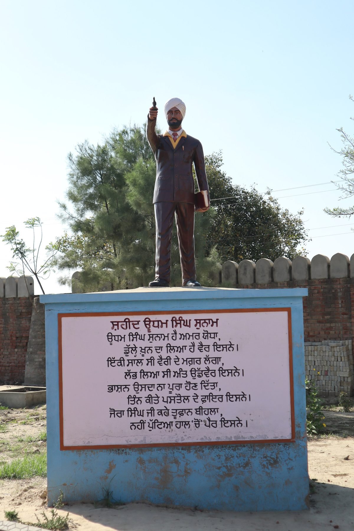 A painted life-size sculpture of Udham Singh in a turban, standing among other figures at a gurdwara museum