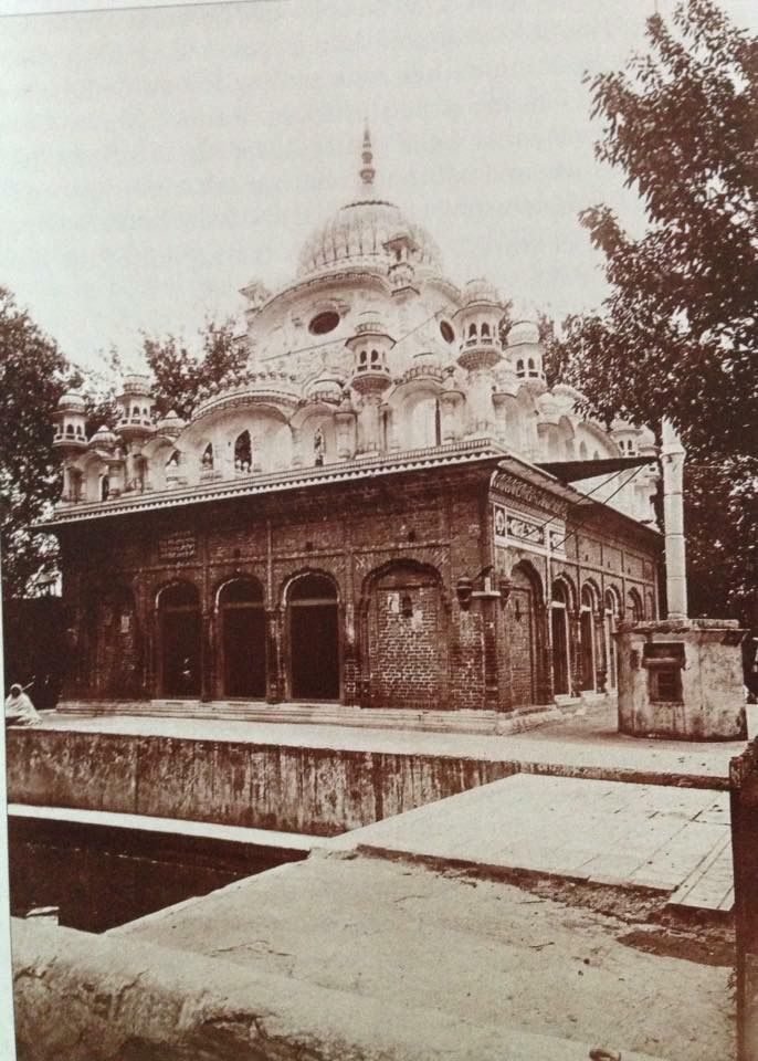 An old black and white photograph of a domed shrine beside a pool, with arched buildings around it